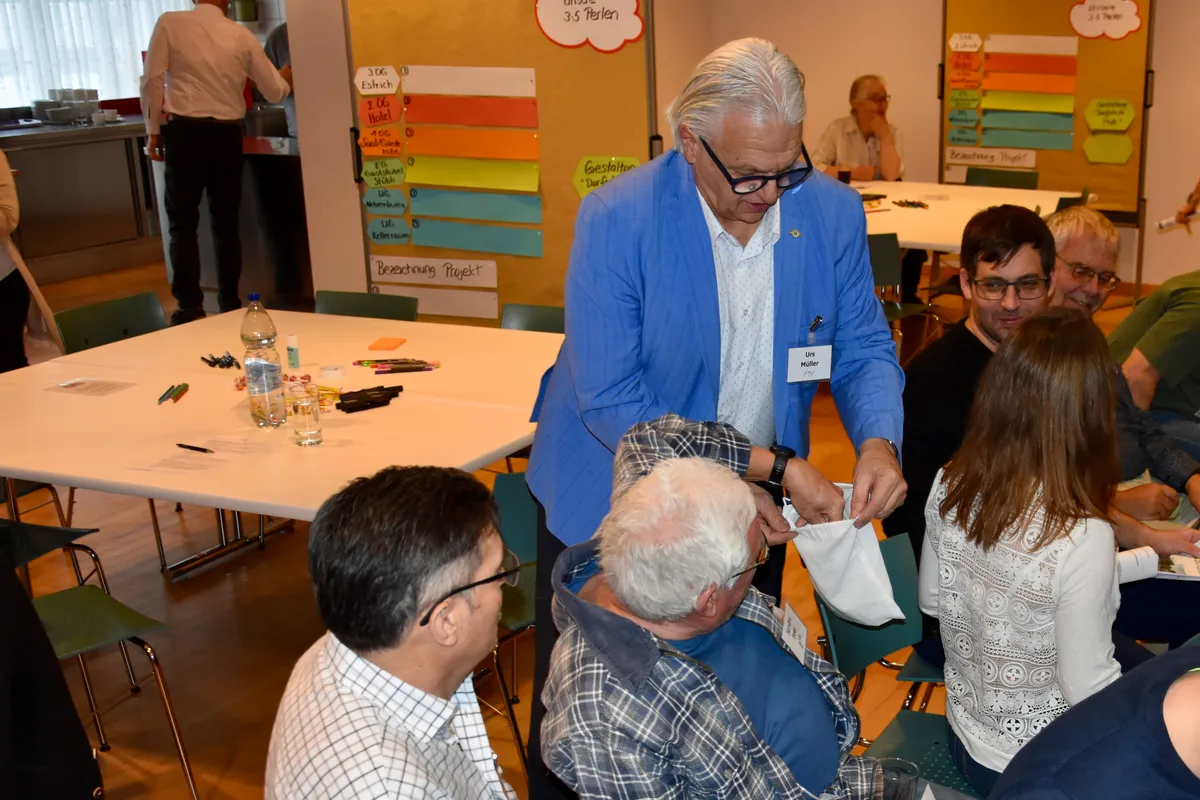 Ein Mann hält einen Beutel in der Hand. Ein anderer greift hinein und zieht etwas heraus. 